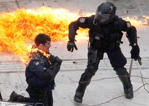 Một cảnh sát Hy Lạp bị lửa cháy bám lên người, trong khi đồng đội của anh ta cố gắng giúp đỡ. Những người biểu tình ném bom xăng vào viên cảnh sát tại thủ đô Athens hôm 23/2. Hàng chục thanh niên đã dùng đá và bom xăng tấn công cảnh sát trong những vụ đụng độ nổ ra sau cuộc biểu tình lớn nằm trong một cuộc tổng đình công. Hy Lạp là tâm điểm của cuộc khủng hoảng nợ công tại khu vực đồng tiền chung châu Âu trong năm 2011. Ảnh: AP
